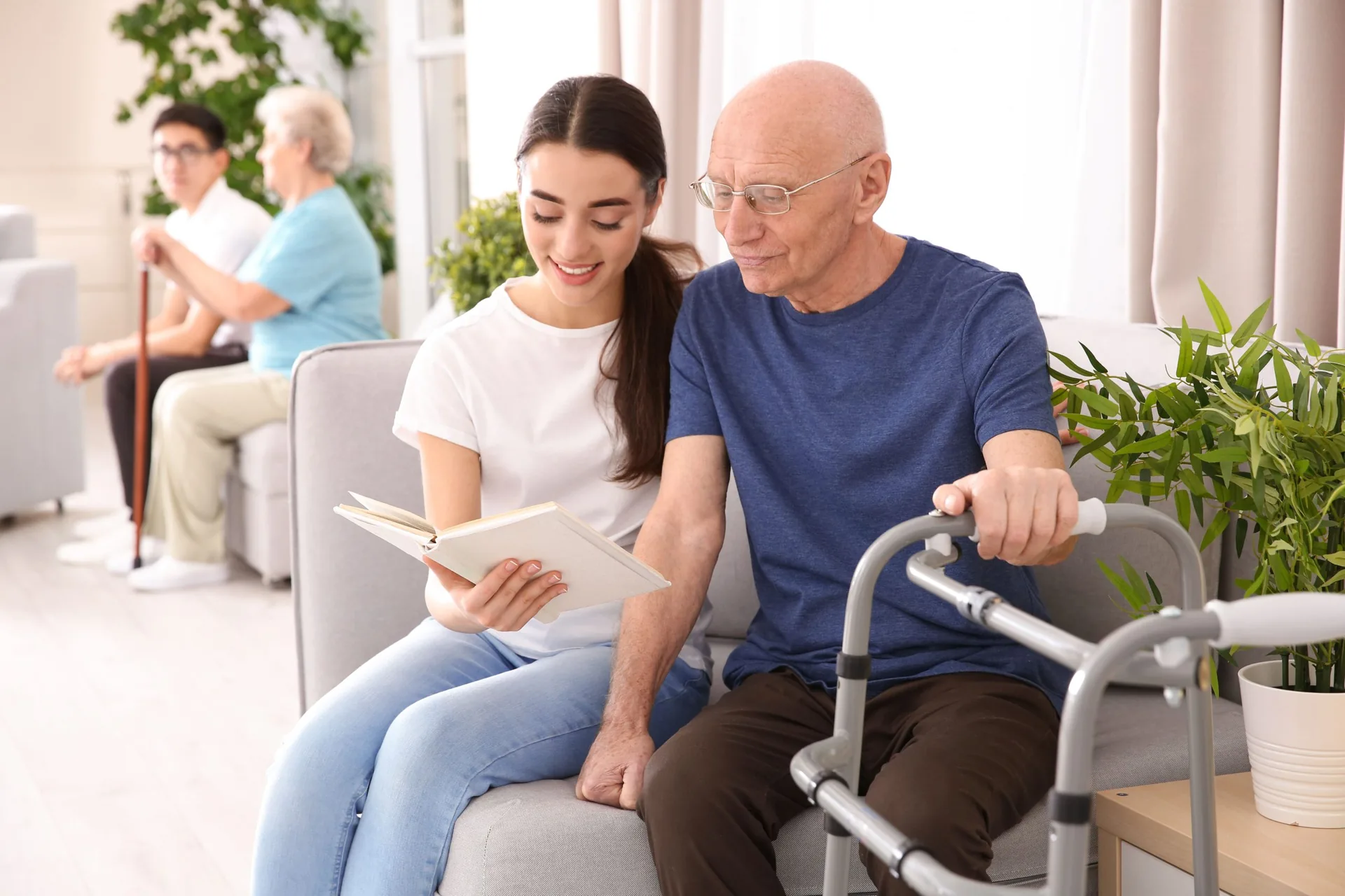 Betreuerin liest einem Senior mit Rollator vor