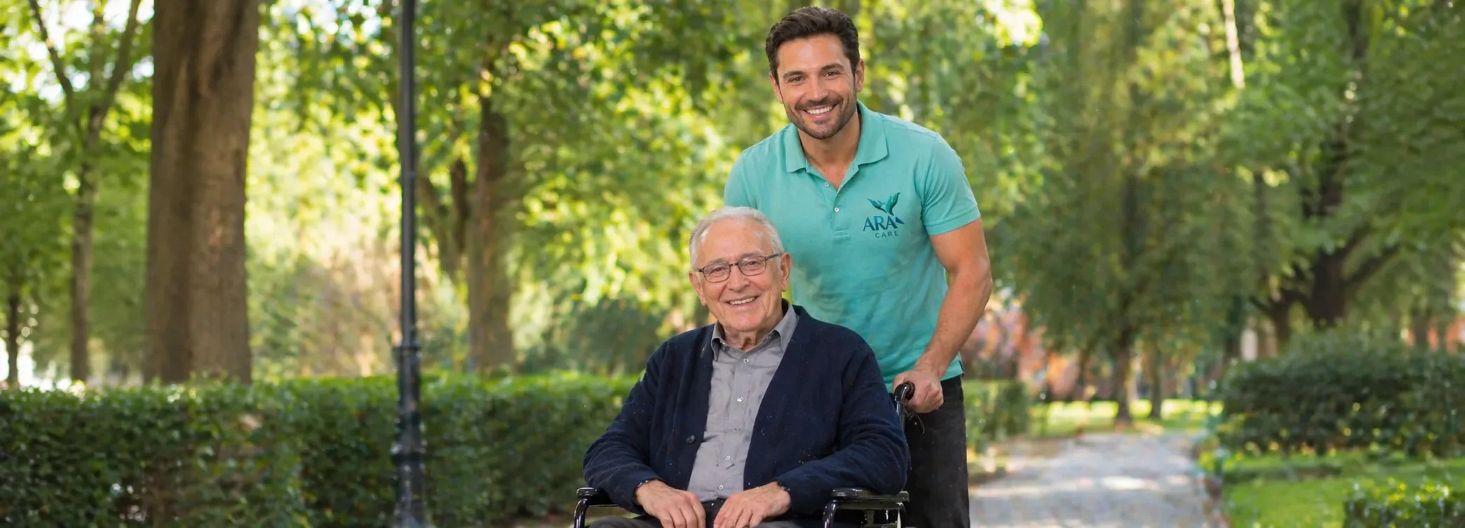 Therapeut begleitet einen Senior im Rollstuhl im Park