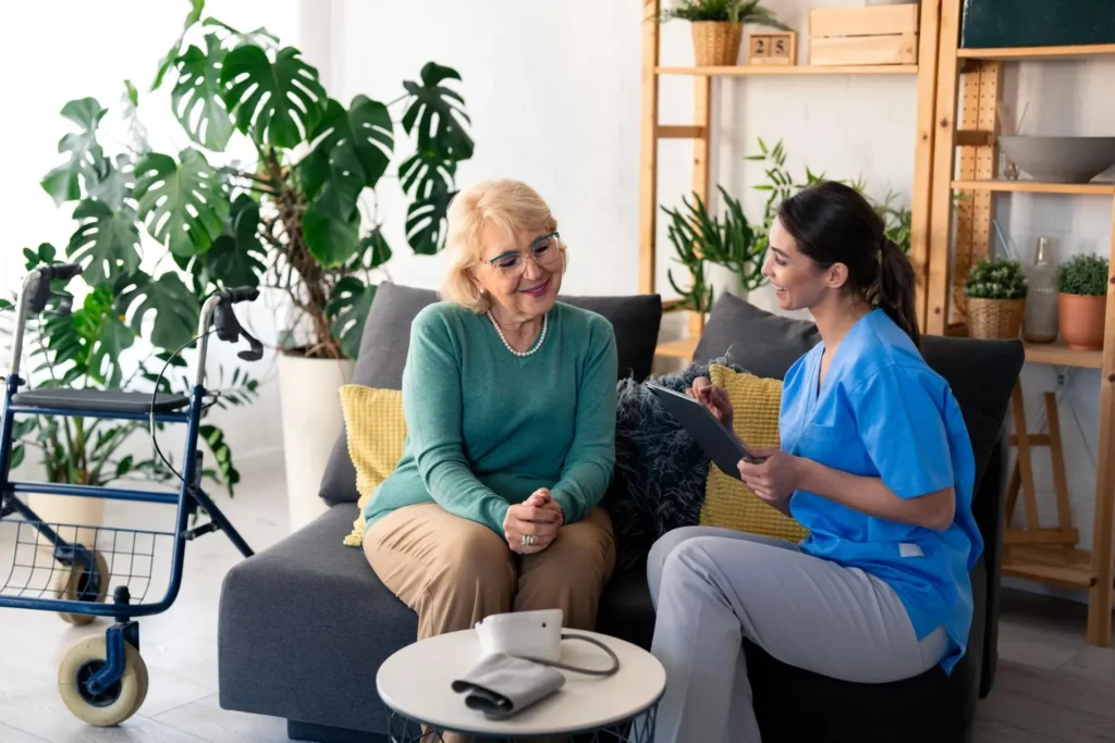 Private Pflege zu Hause: Pflegekraft im Gespräch mit einer Seniorin