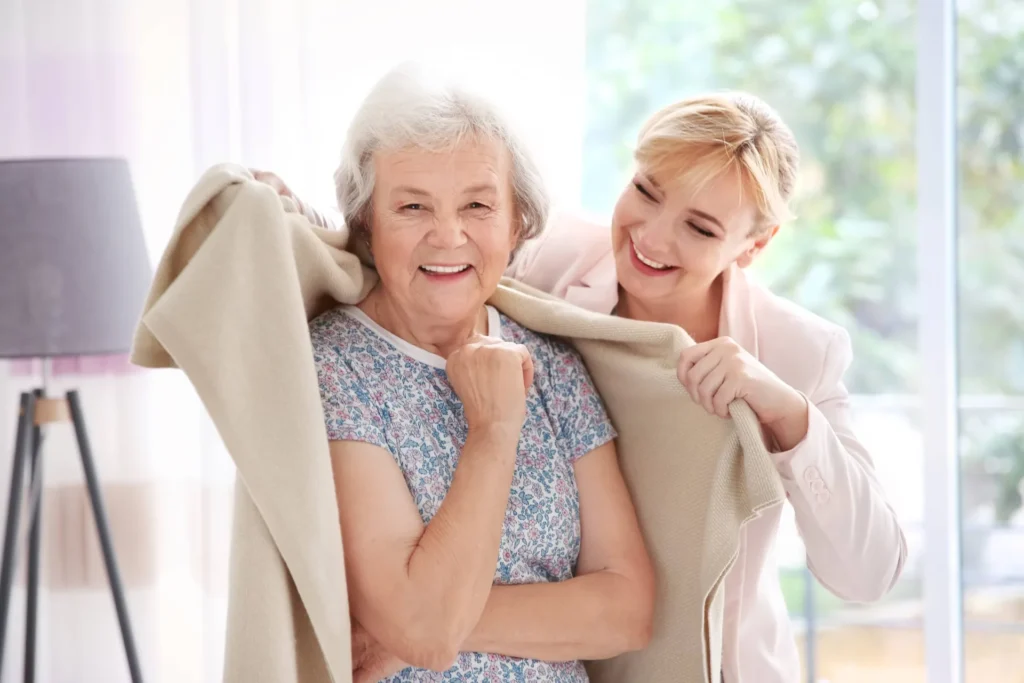 Seniorin lacht gemeinsam mit ihrer Betreuerin